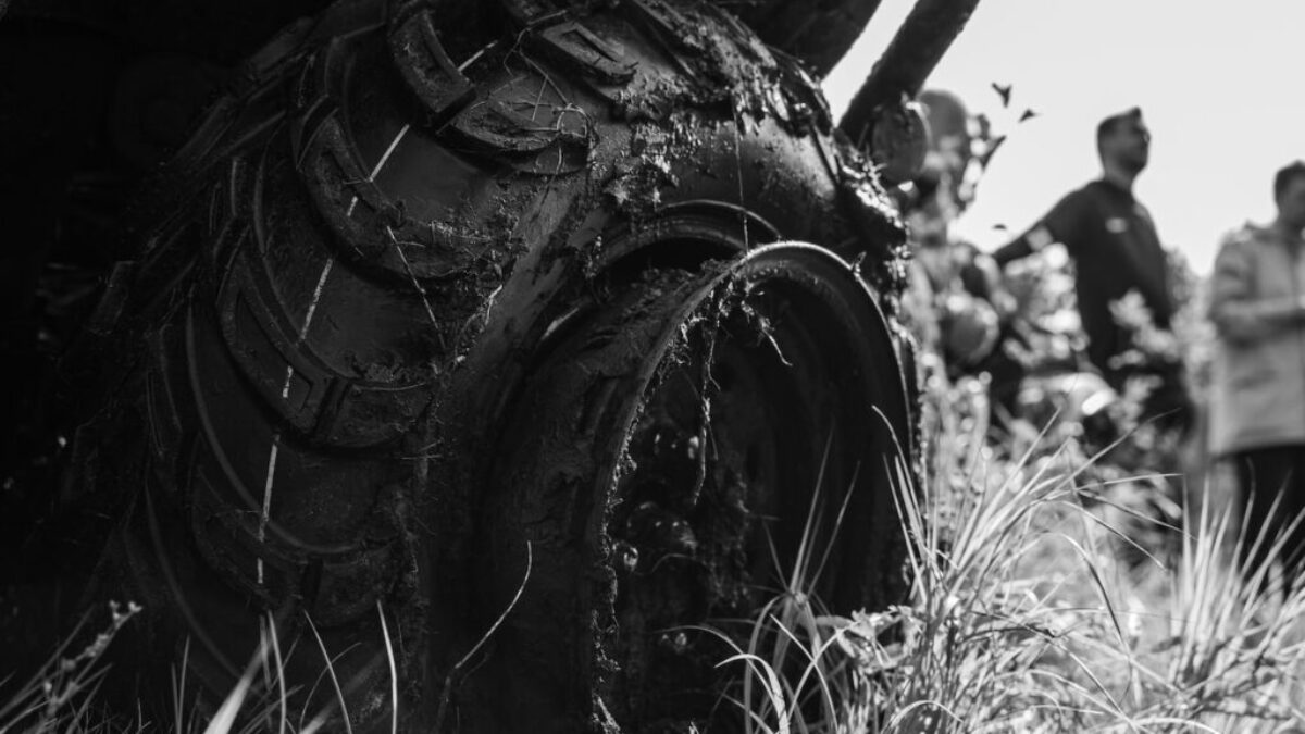 a black and white photo of a group of people looking at a tire