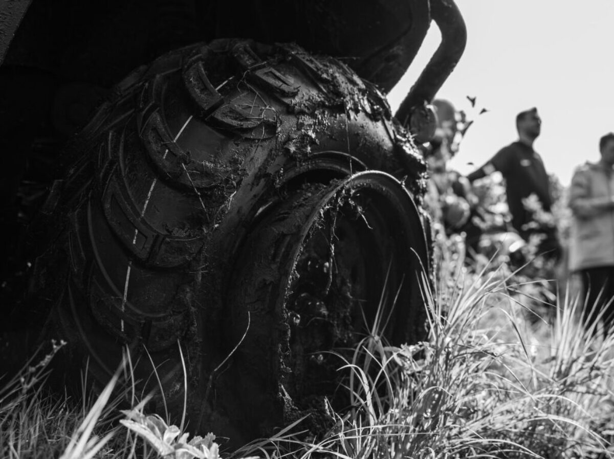 a black and white photo of a group of people looking at a tire