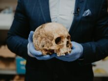 person in blue long sleeve shirt holding brown skull