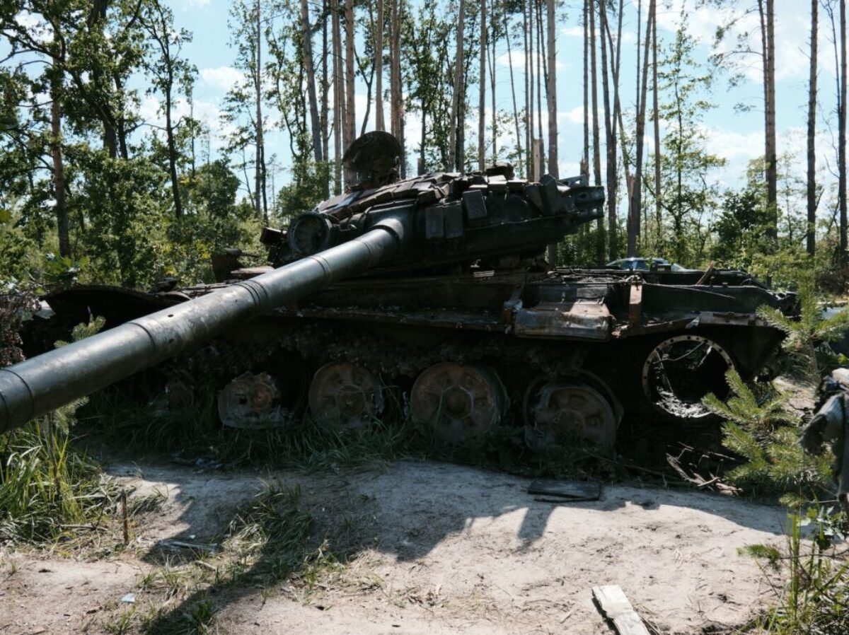 an old tank sitting in the middle of a forest