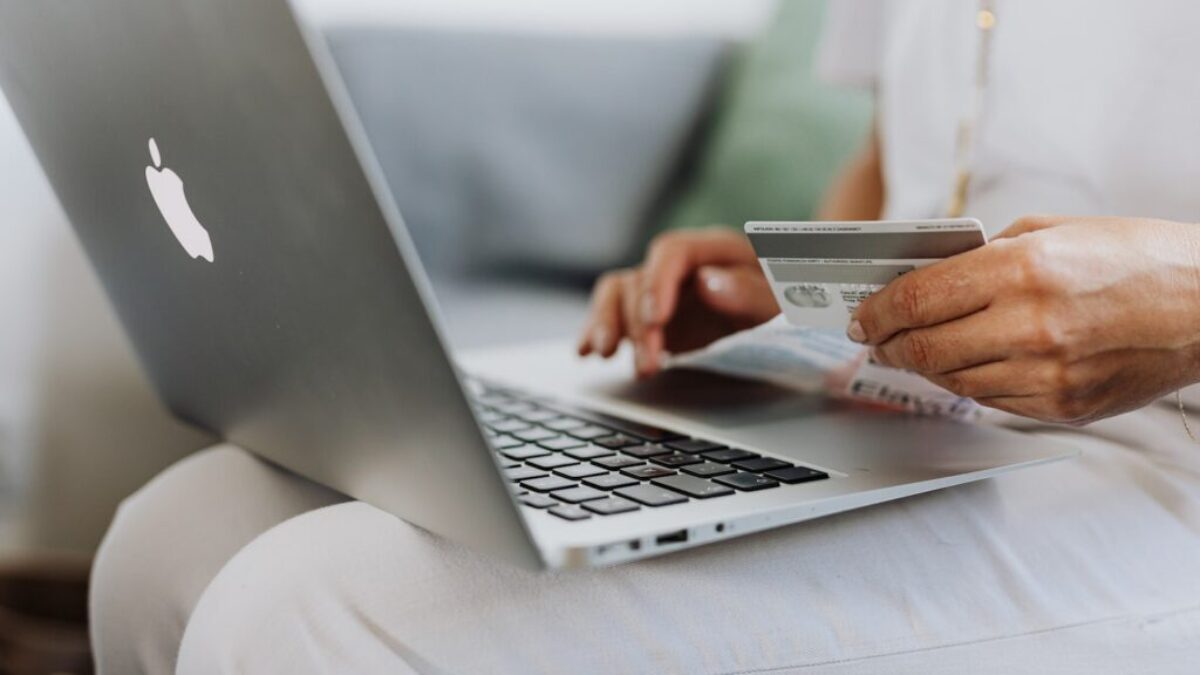 Person Using a Macbook and Holding a Credit Card