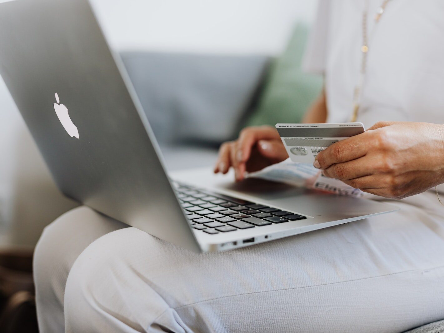 Person Using a Macbook and Holding a Credit Card