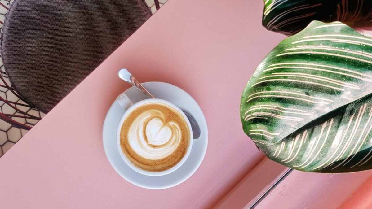 cup of coffee on saucer with teaspoon on pink tabletop