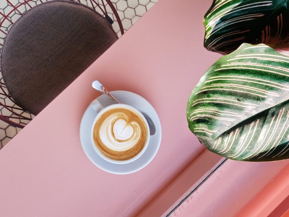 cup of coffee on saucer with teaspoon on pink tabletop