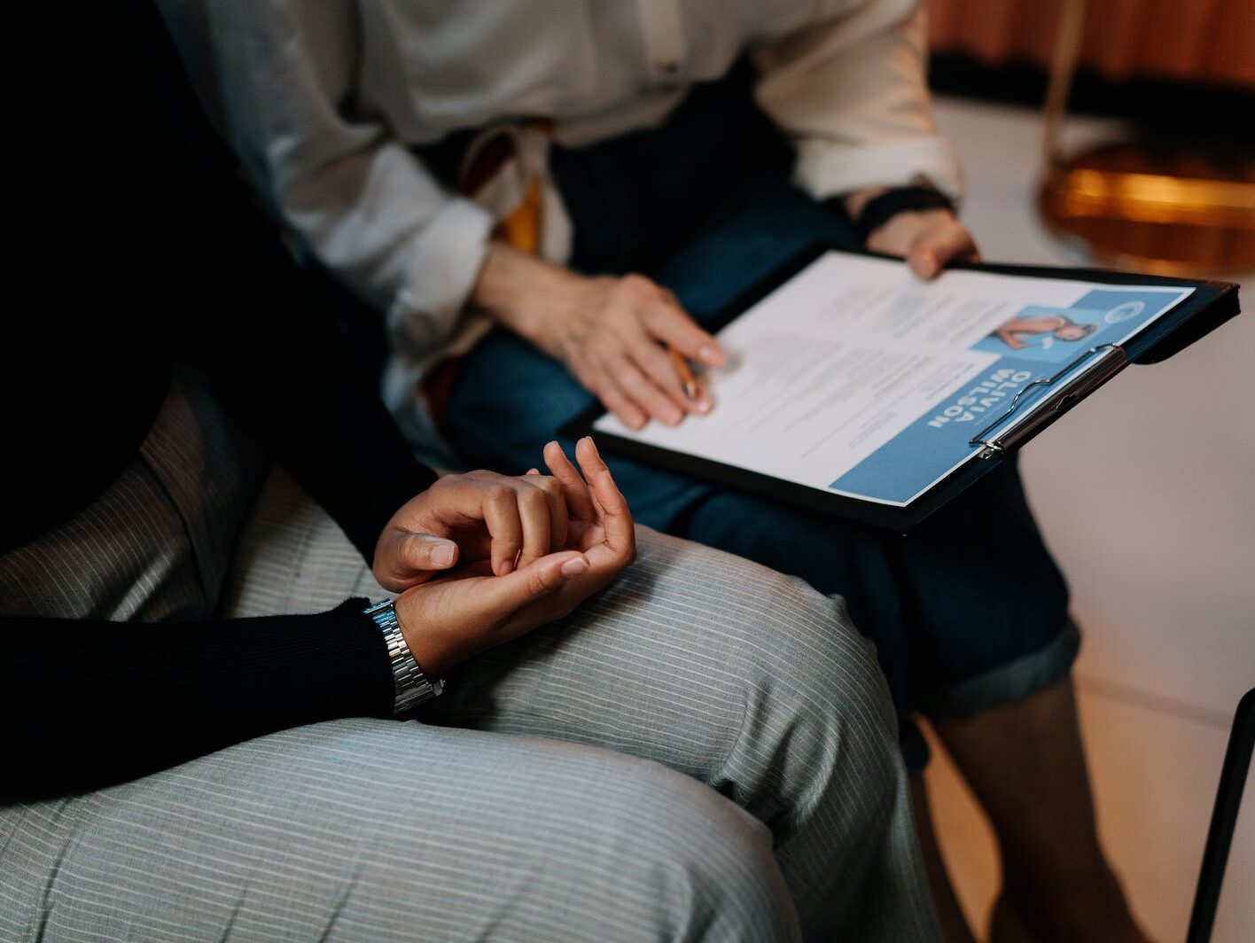 Person in White Long Sleeve Shirt Holding a Clipboard with Resume