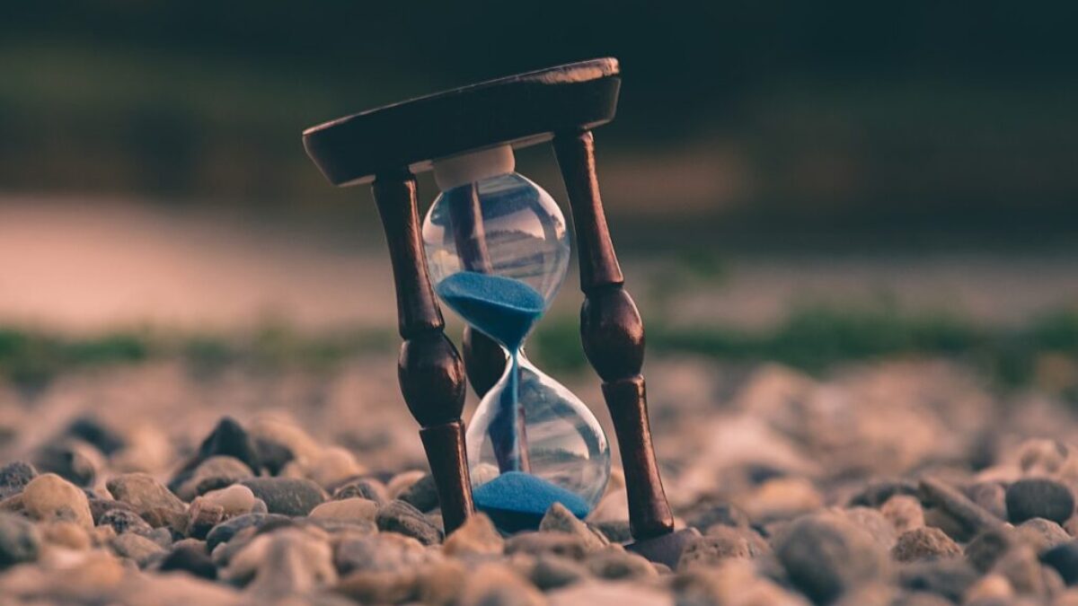 selective focus photo of brown and blue hourglass on stones