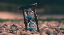 selective focus photo of brown and blue hourglass on stones