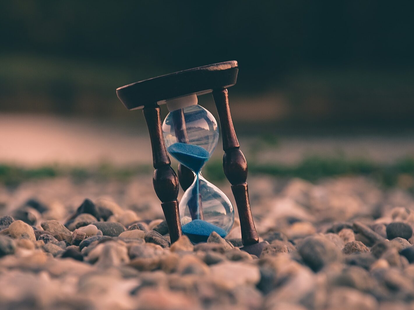 selective focus photo of brown and blue hourglass on stones