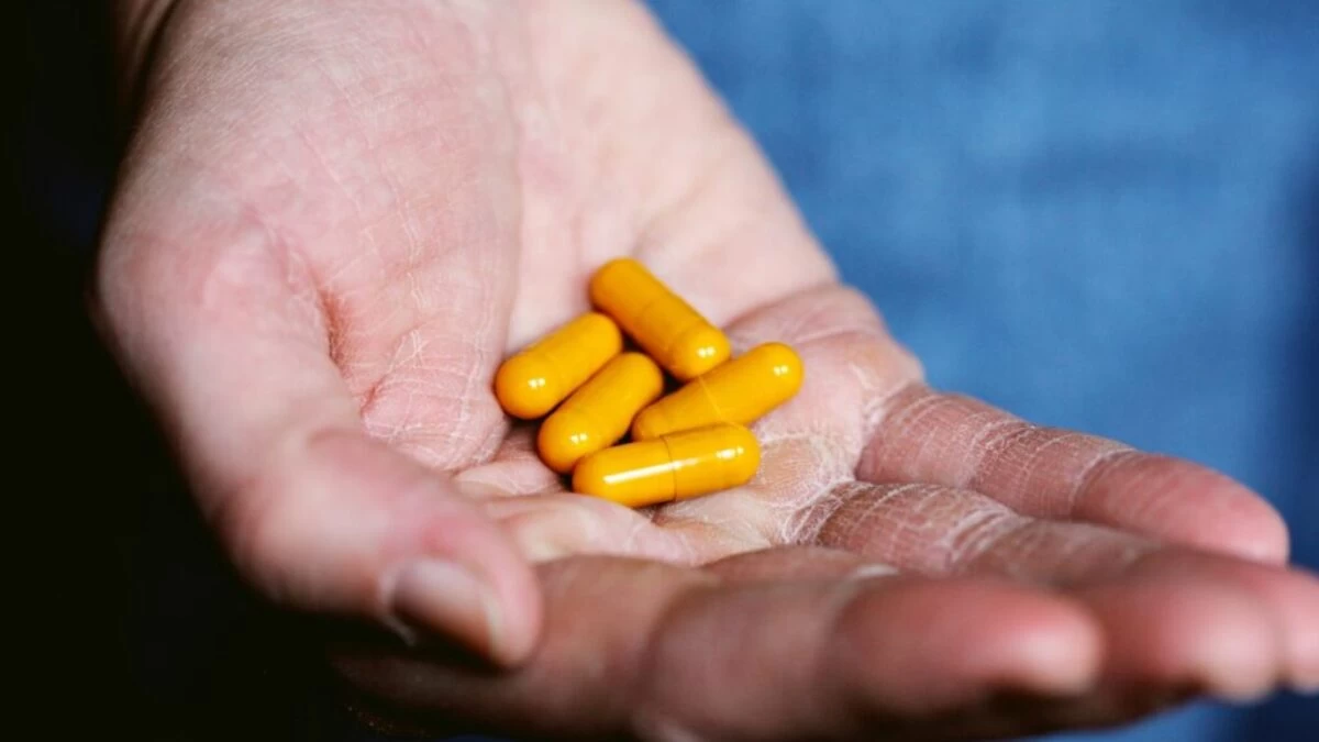 yellow medication pill on persons hand