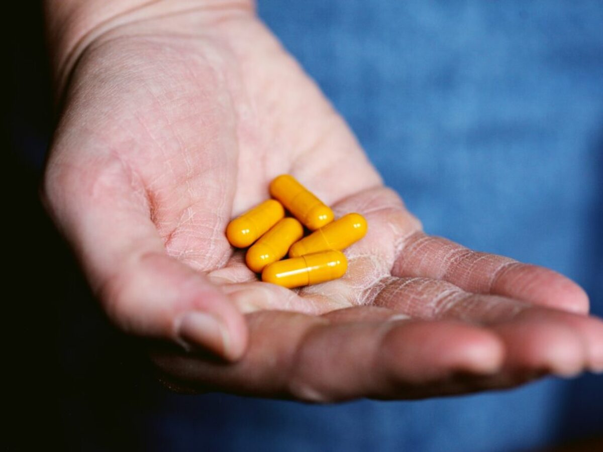 yellow medication pill on persons hand