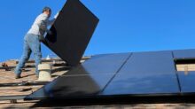 man in white dress shirt and blue denim jeans sitting on white and black solar panel