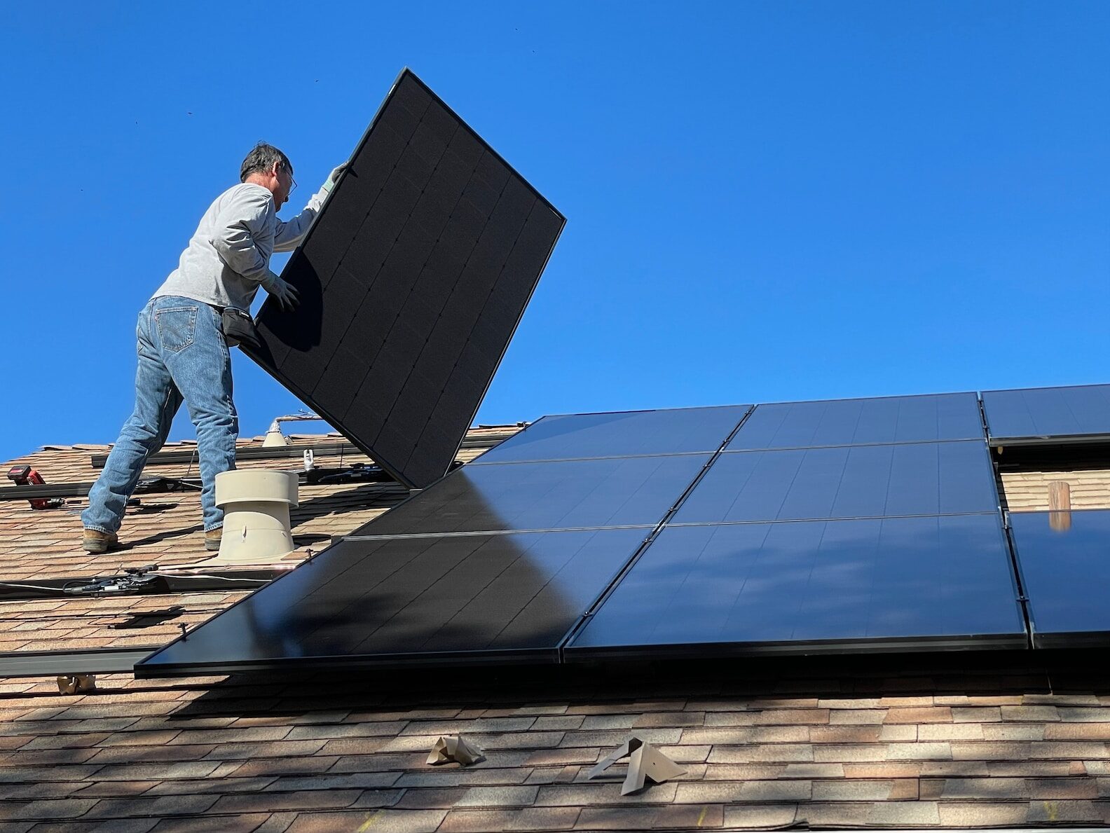 man in white dress shirt and blue denim jeans sitting on white and black solar panel