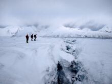 2 person walking on snow covered ground during daytime