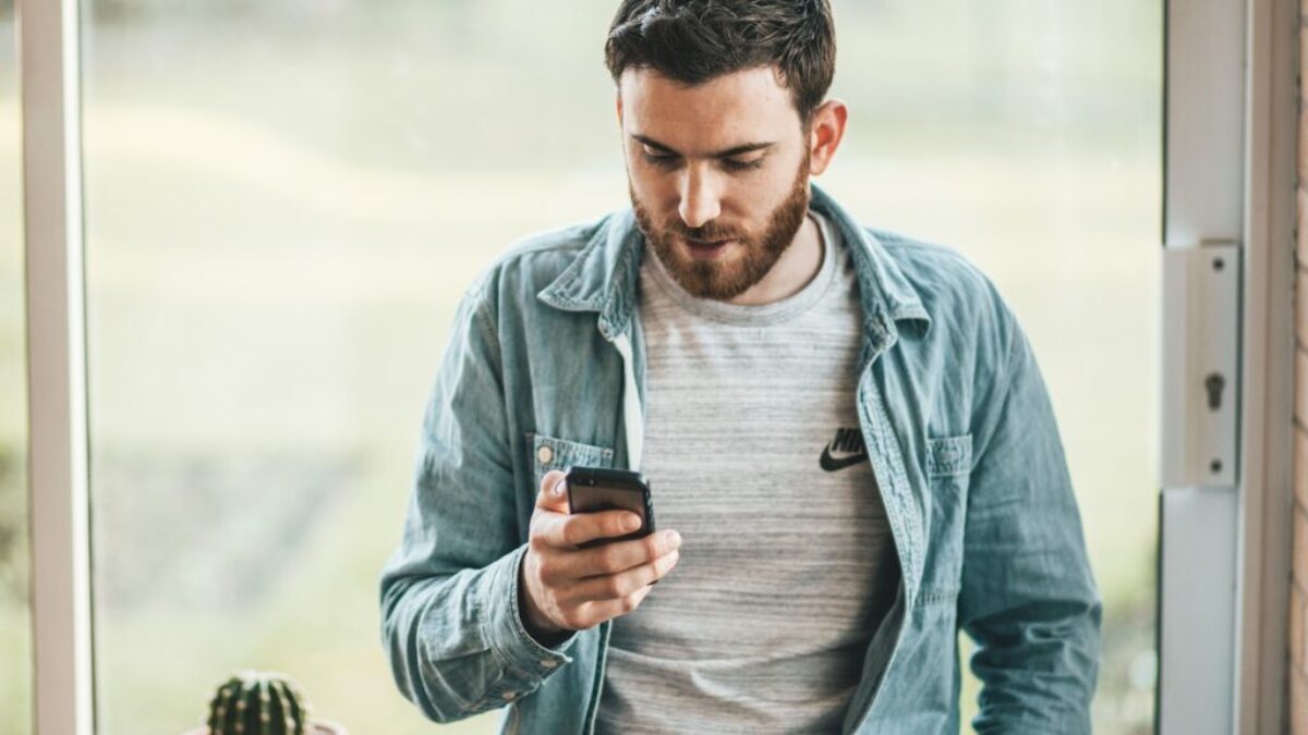 man holding a smartphone near the window