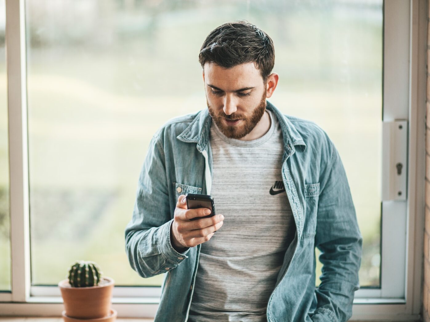 man holding a smartphone near the window