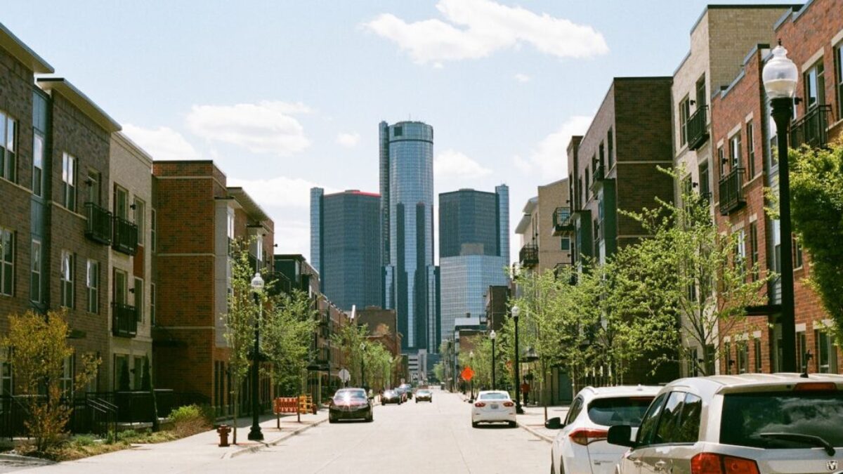 cars parked on side of the road near high rise buildings during daytime