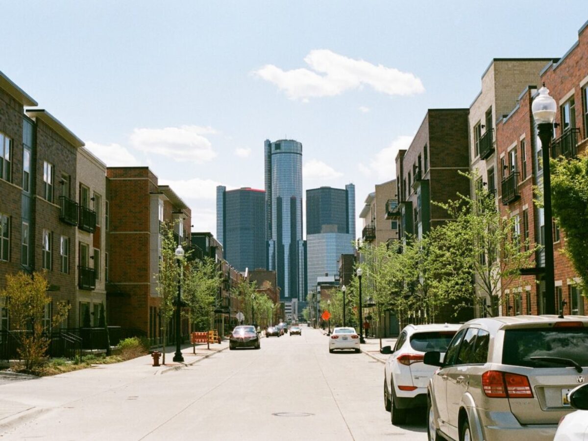 cars parked on side of the road near high rise buildings during daytime