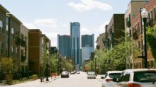 cars parked on side of the road near high rise buildings during daytime