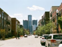cars parked on side of the road near high rise buildings during daytime