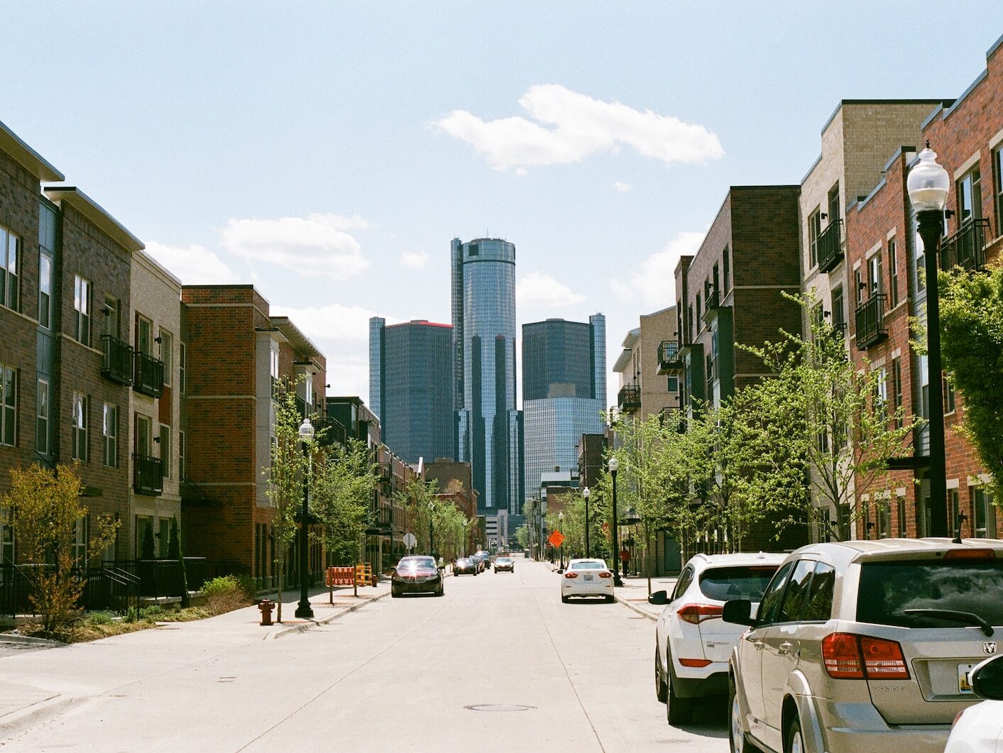 cars parked on side of the road near high rise buildings during daytime