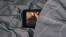 black Android smartphone on gray bed sheet