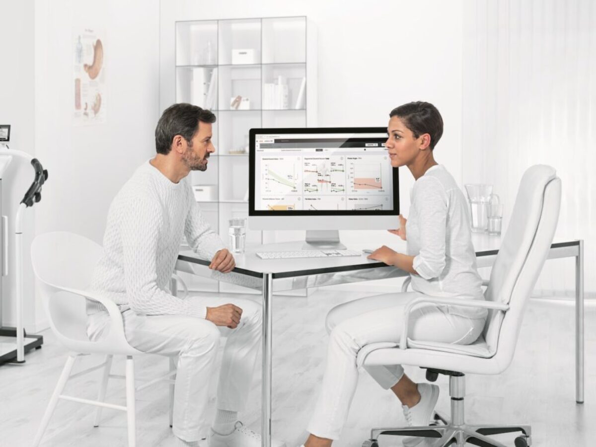 man in white dress shirt sitting on white chair in front of computer