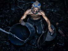 a man with a mask on holding a bucket