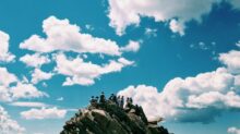 people on rock formation under white cloudy sky