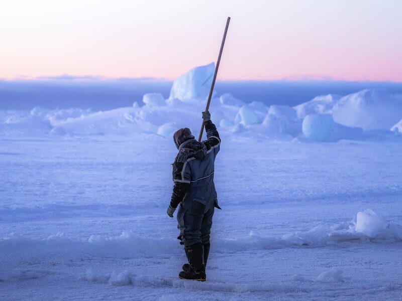 person in black winter jacket holding black stick on snow covered ground during daytime