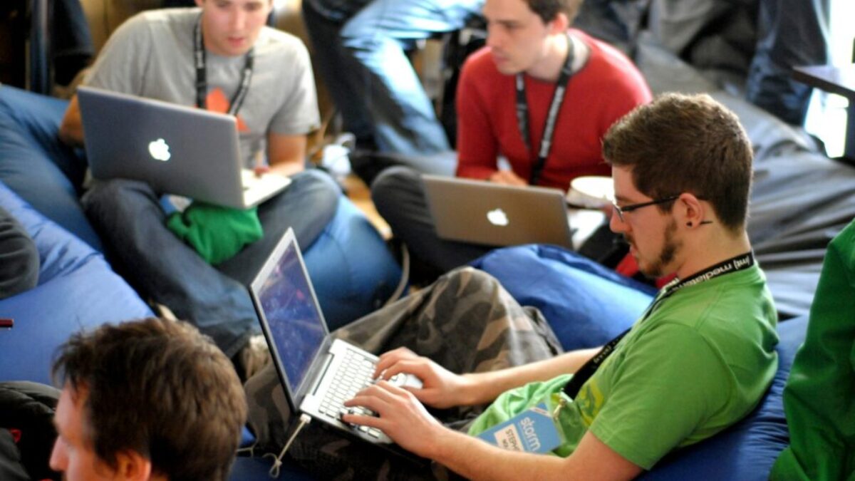 man sitting on blue bean bag usinglaptop