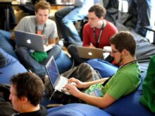 man sitting on blue bean bag usinglaptop