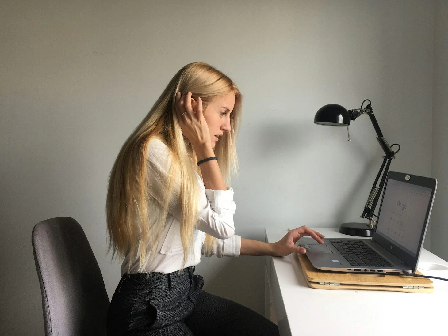 woman in white long sleeve shirt and black pants sitting on black office rolling chair