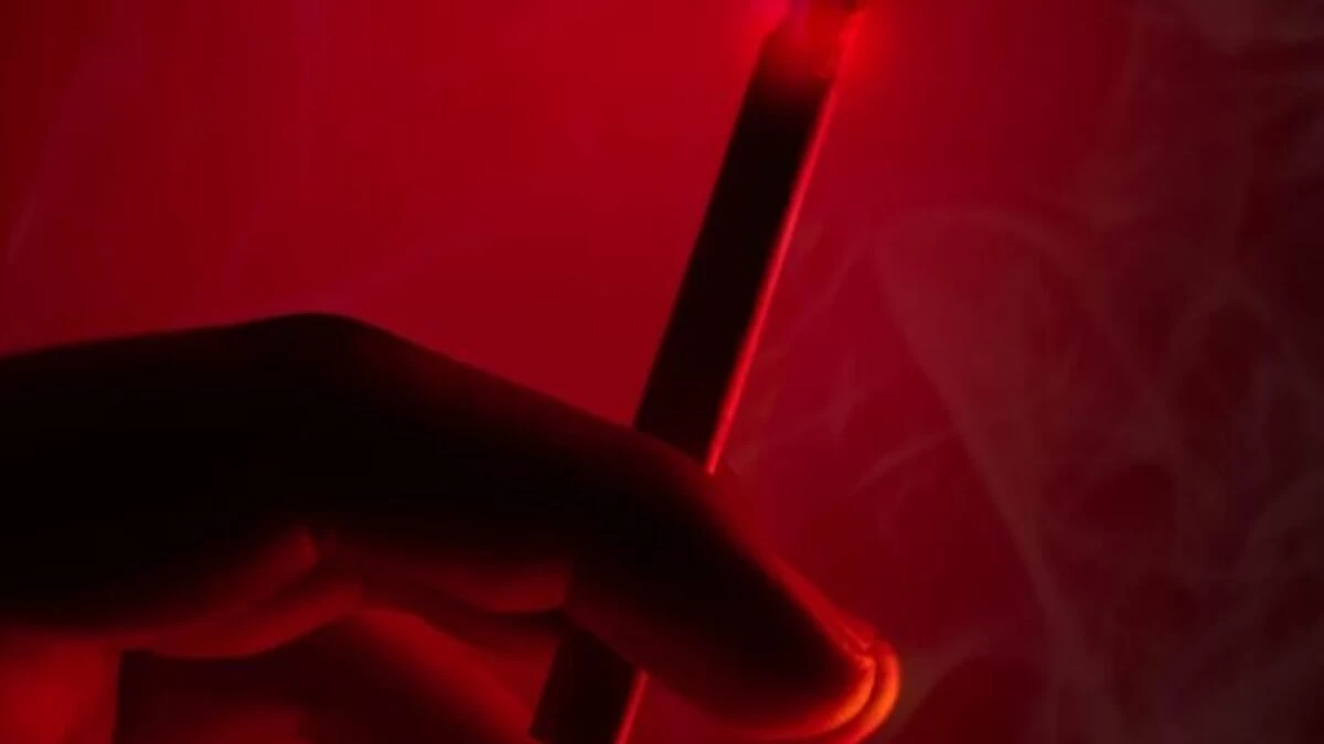 person holding lighted cigarette stick