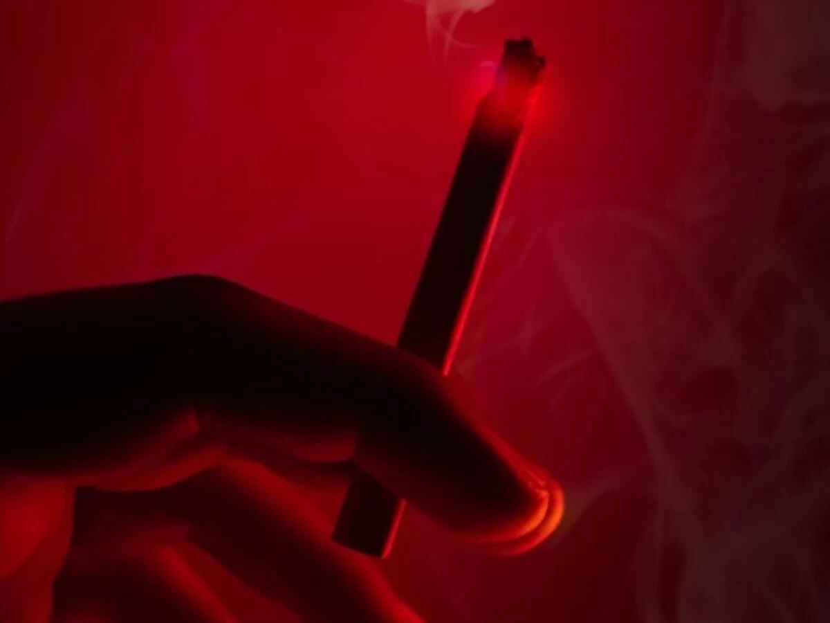 person holding lighted cigarette stick