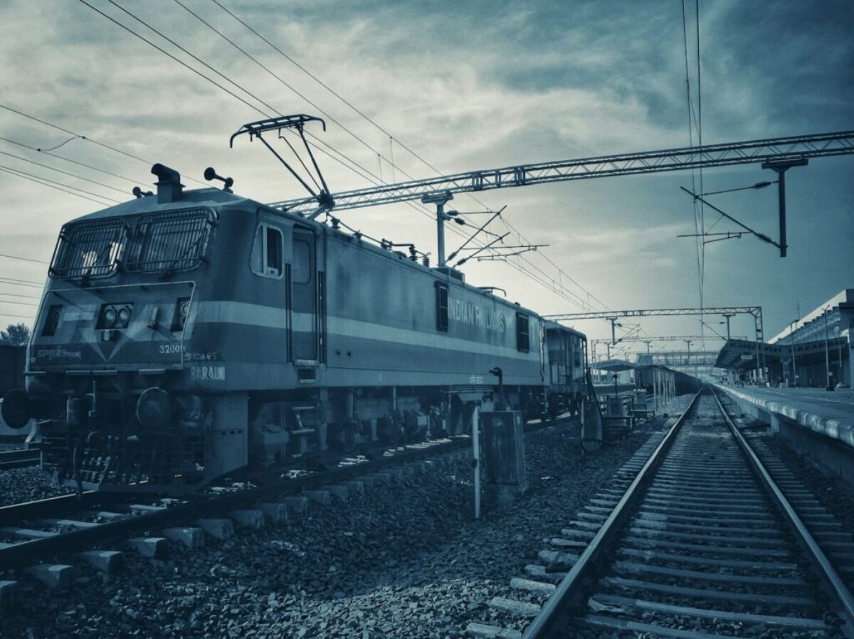 green train on rail tracks under cloudy sky