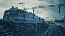green train on rail tracks under cloudy sky