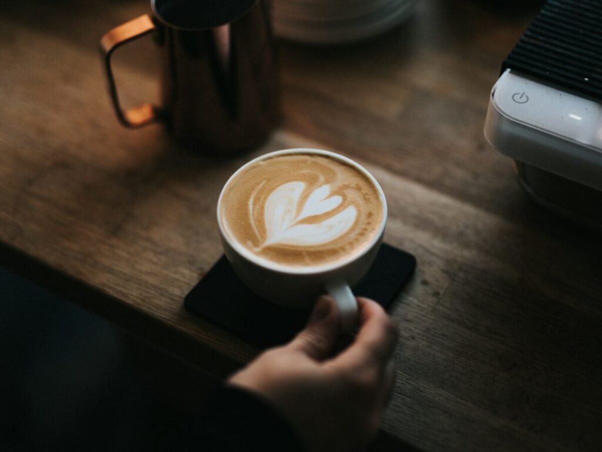 a person holding a cup of coffee on top of a wooden table