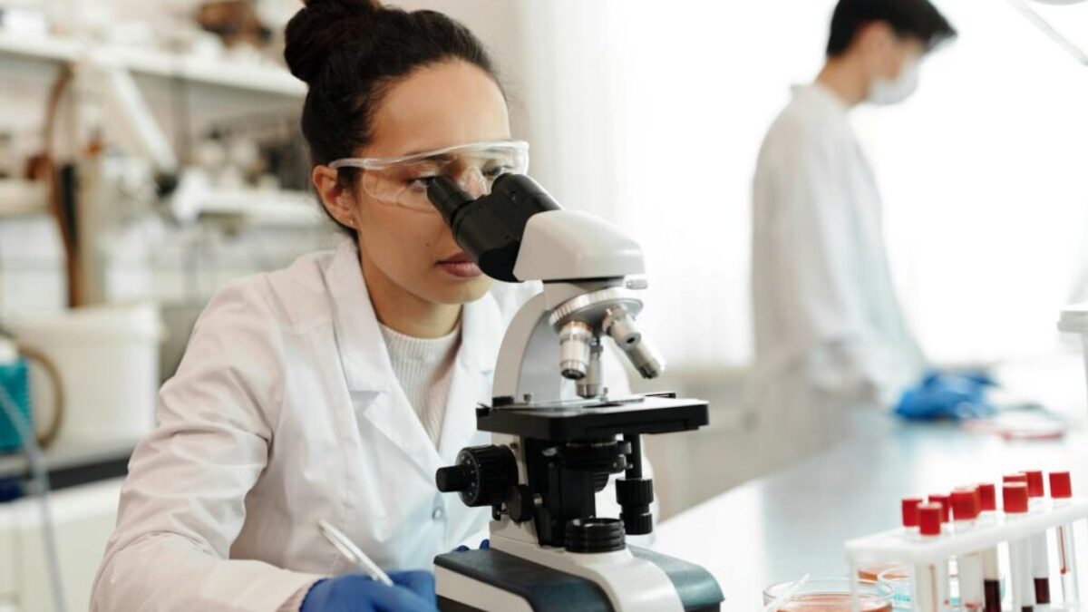 Female Scientist in White Lab Coat Using a Microscope
