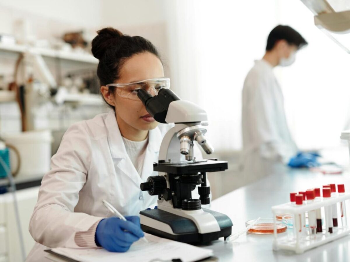 Female Scientist in White Lab Coat Using a Microscope