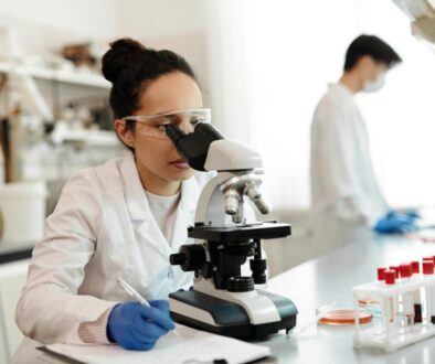 Female Scientist in White Lab Coat Using a Microscope