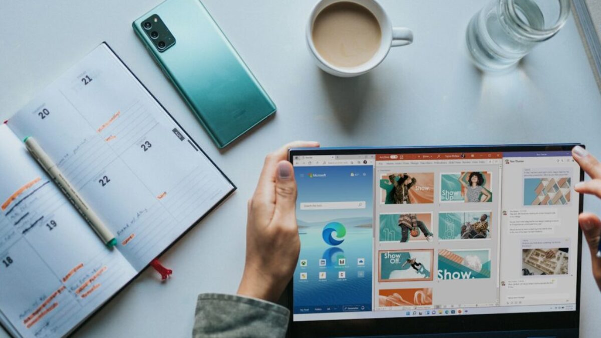 person using Windows 11 computer beside white ceramic mug on white table