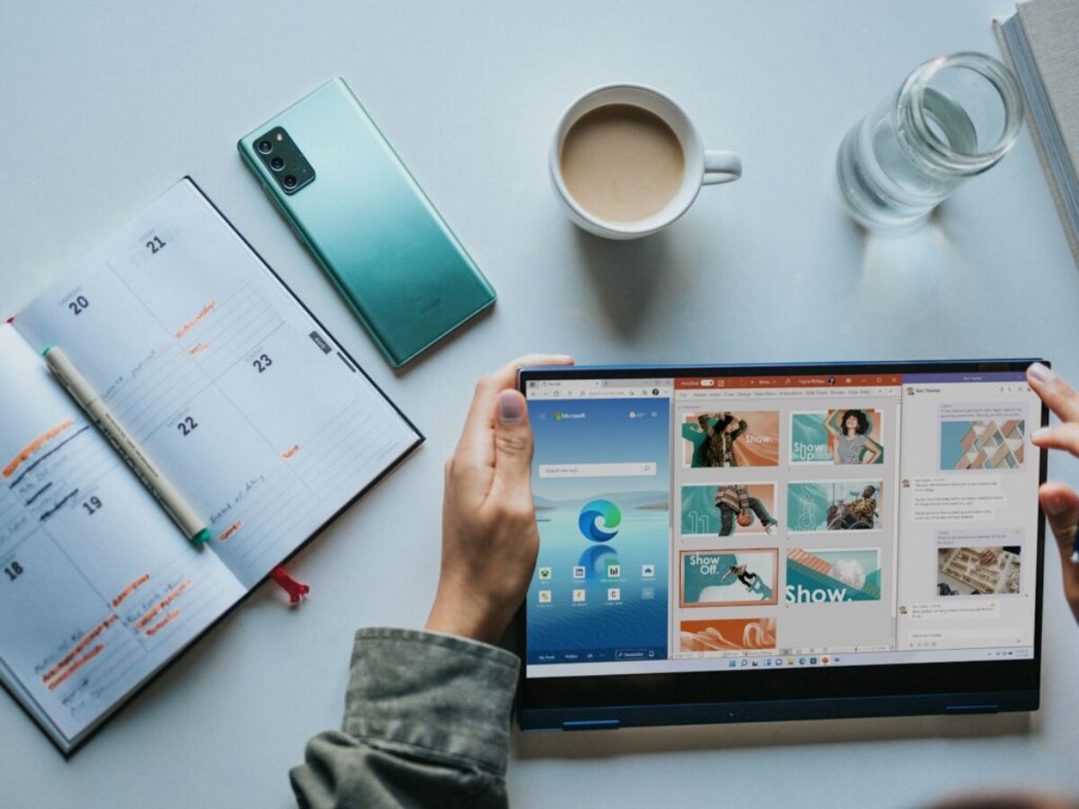 person using Windows 11 computer beside white ceramic mug on white table