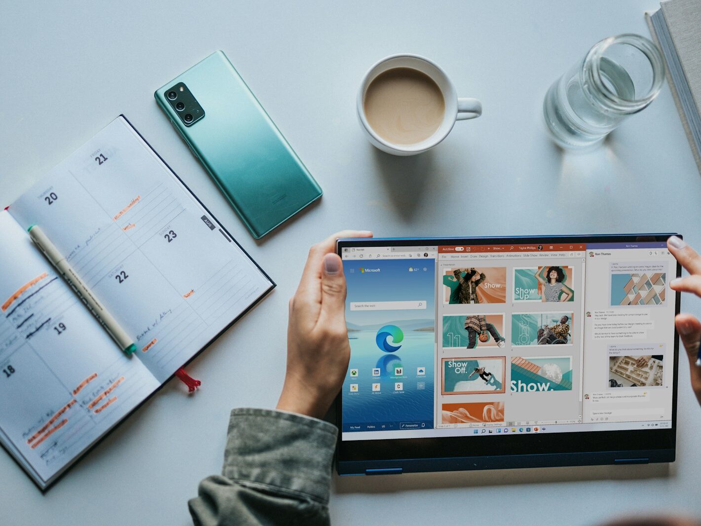person using Windows 11 computer beside white ceramic mug on white table