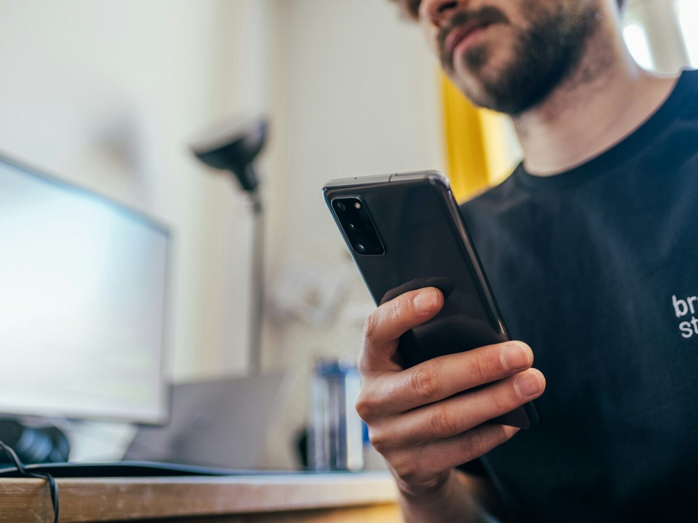man in black crew neck shirt holding black iphone 5