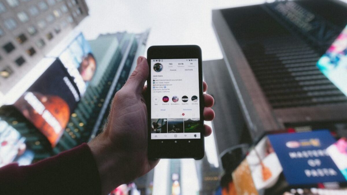 high angle photo of person holding turned on smartphone with tall buildings background