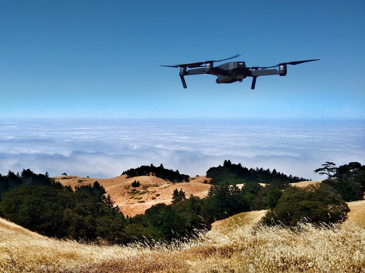 black drone on air over cloudy sky at daytime