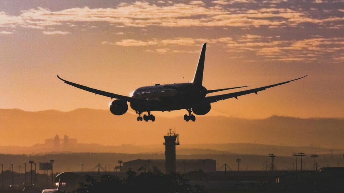 White Passenger Plane Flying over the City during Sunset