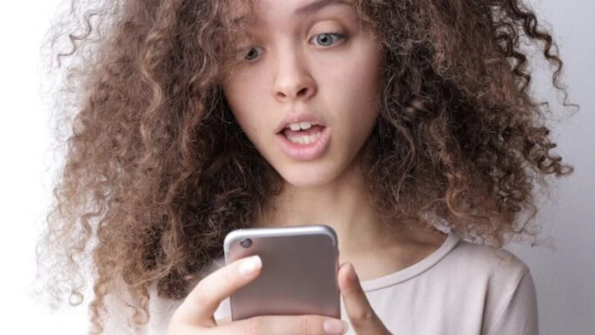 Surprised young woman browsing mobile phone