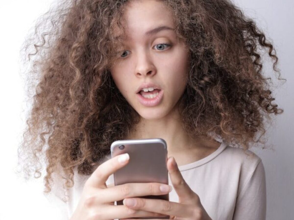 Surprised young woman browsing mobile phone