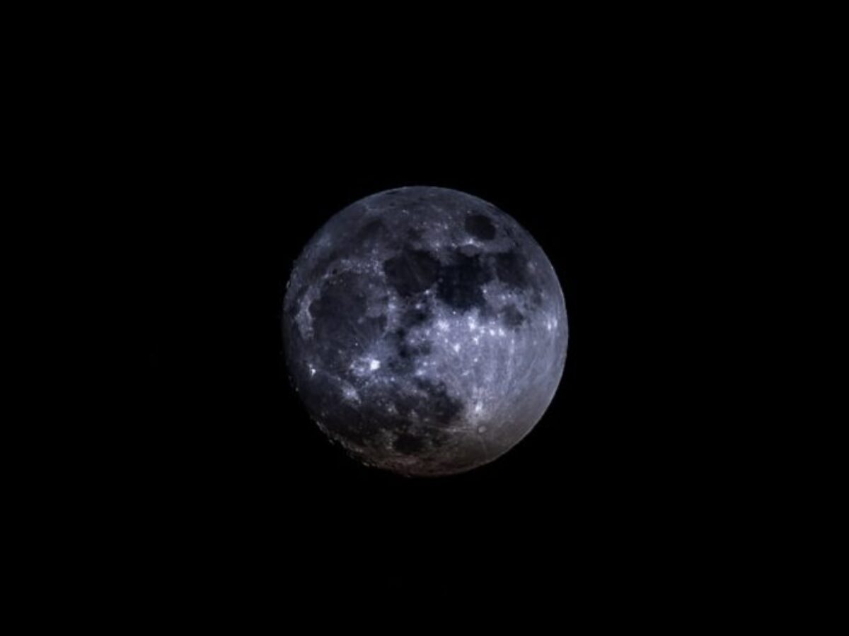 a full moon is seen in the dark sky